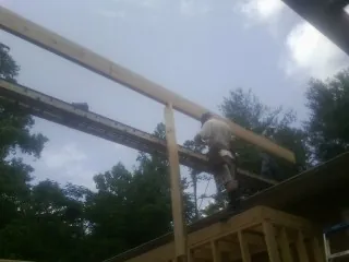 Carpenter setting a ridge beam over a new addition frame — Ice Dam Removal by Roofing Brothers in Barnstead