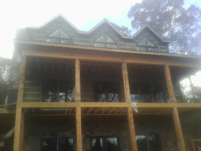 Dormers and porch framing on a large log home under construction — Roof Coating work by our crew in Barnstead
