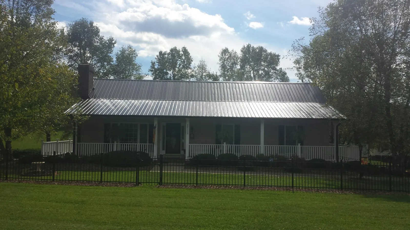 Gray metal roof on a brick ranch with a full width front porch — Gutter Guard Installation work by our crew in Barnstead