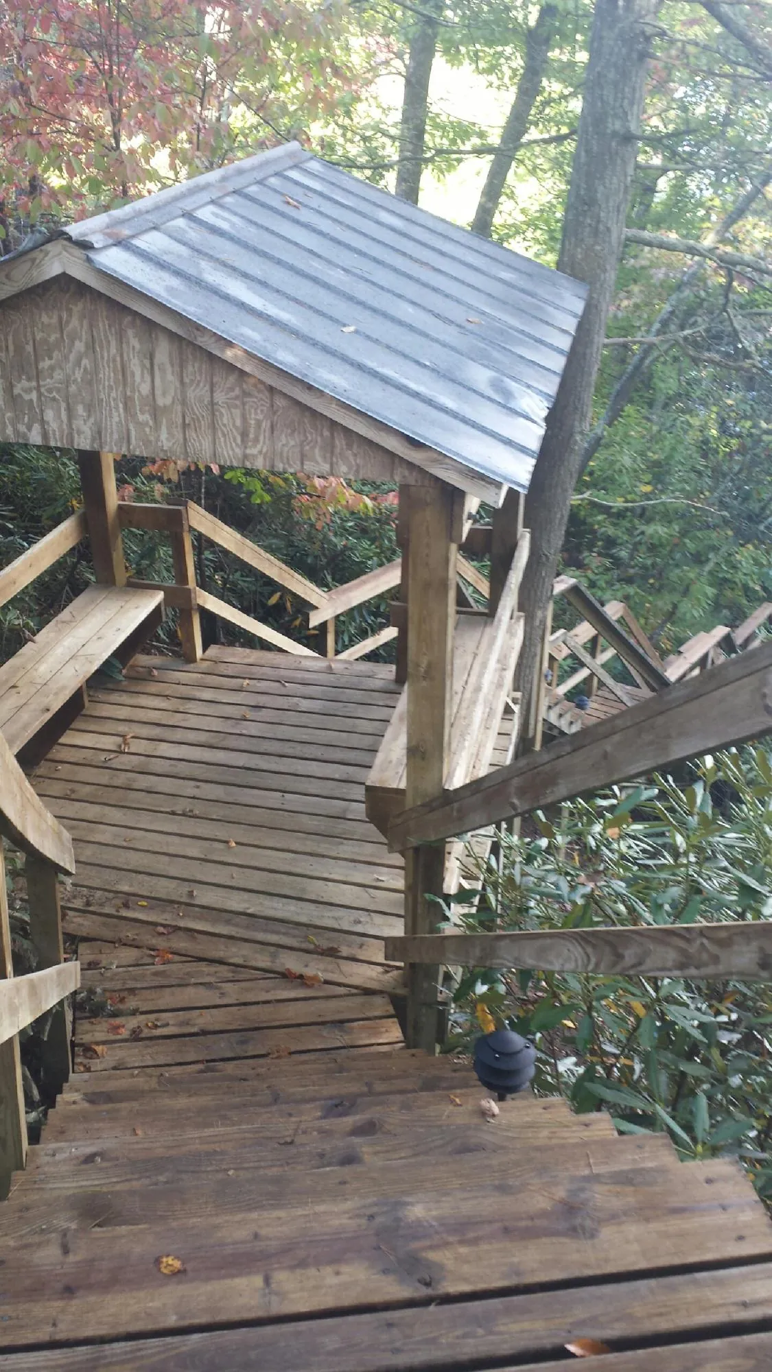 Metal roofed shelter over wooden steps on a wooded walkway — Skylight Repair & Installation work by our crew in Barnstead