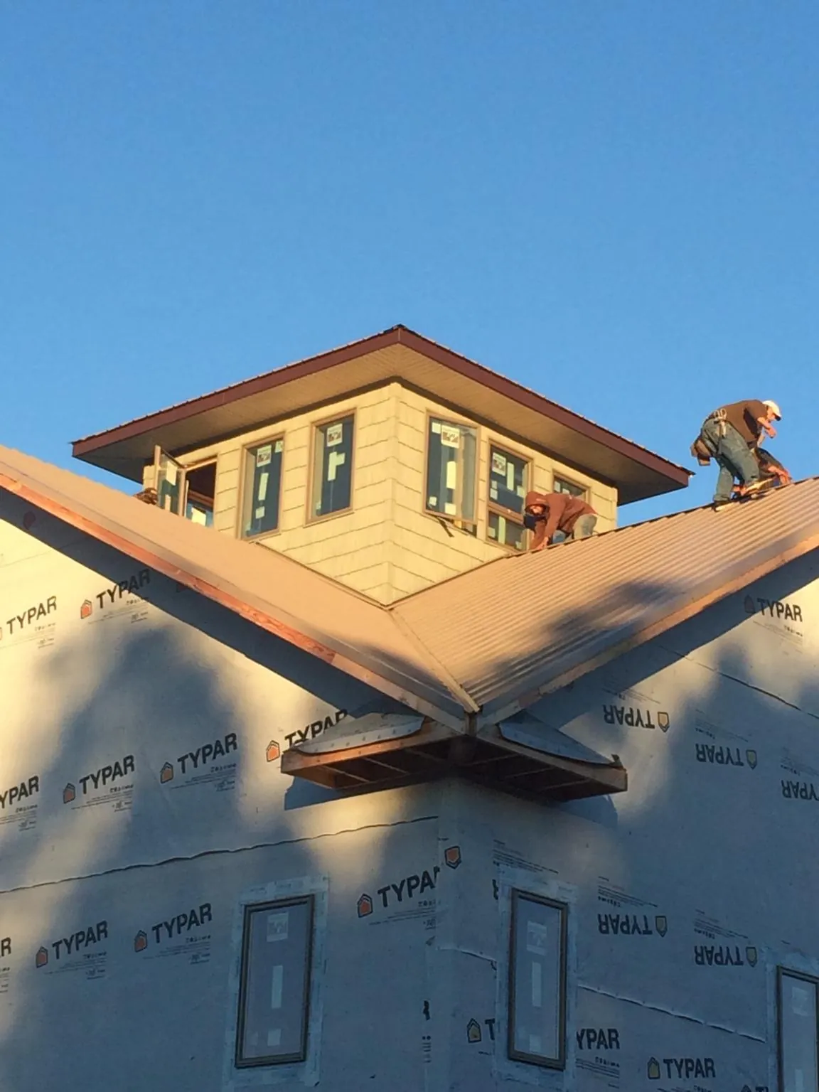 Roofers working around a rooftop cupola on a new metal roof at sunset — Roof Waterproofing in Barnstead by Roofing Brothers